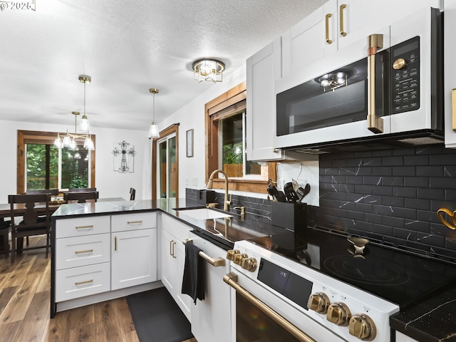 54934 E Kirkwood Dr, Sandy, OR 97055 - kitchen with white appliances, a peninsula, a sink, dark countertops, and dark wood finished floors