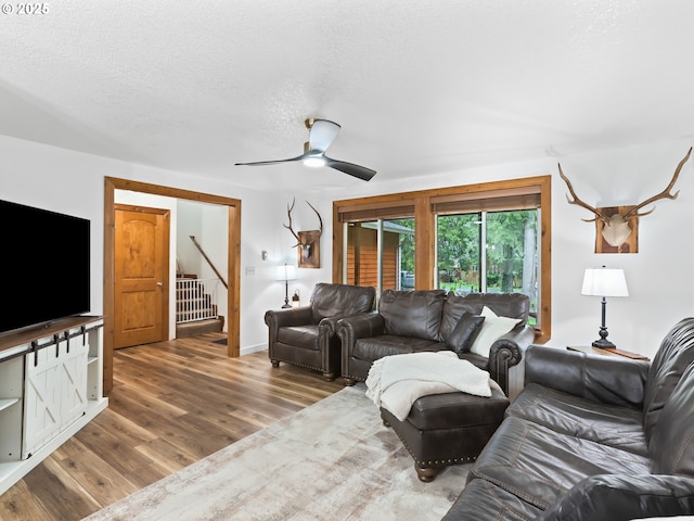 54934 E Kirkwood Dr, Sandy, OR 97055 - living room with wood finished floors, stairway, ceiling fan, and a textured ceiling