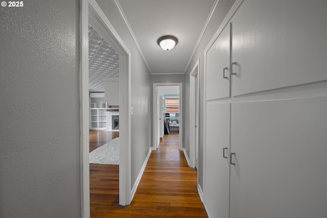 hallway with wood finished floors, ornamental molding, and baseboards