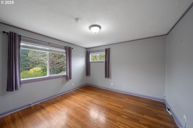 spare room with hardwood / wood-style flooring, baseboards, and a textured ceiling