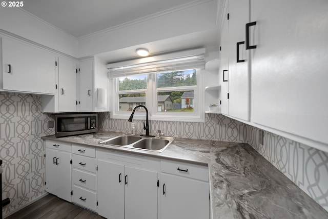kitchen featuring stainless steel microwave, a sink, white cabinetry, crown molding, and light countertops