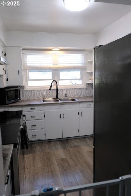 kitchen featuring stainless steel appliances, a sink, white cabinets, dark wood-type flooring, and plenty of natural light