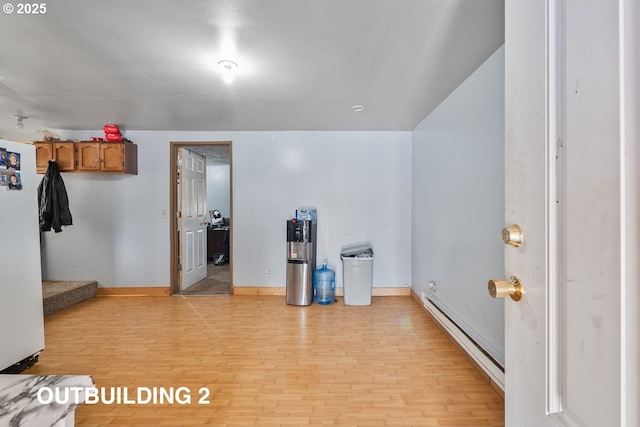 interior space with light wood-type flooring, a baseboard radiator, and baseboards