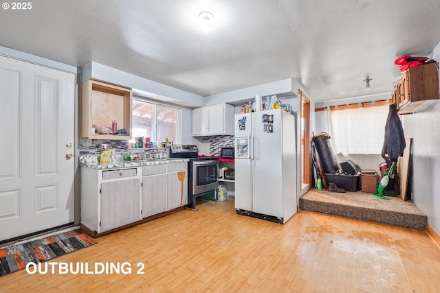 kitchen with tasteful backsplash, white refrigerator with ice dispenser, light wood-style flooring, stainless steel electric stove, and light countertops