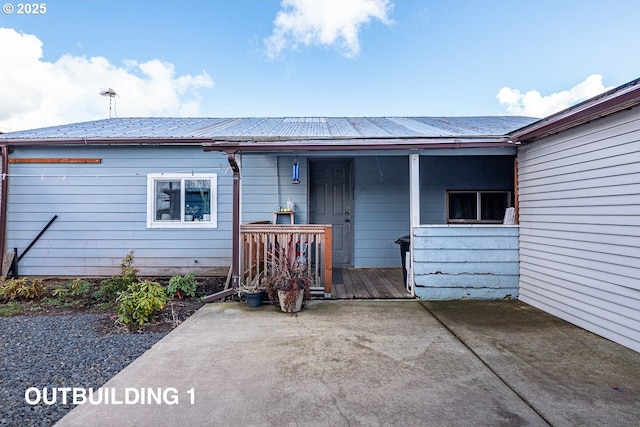 rear view of house featuring a porch and metal roof