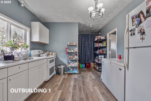 kitchen featuring a textured ceiling, white appliances, white cabinetry, light countertops, and light wood-type flooring