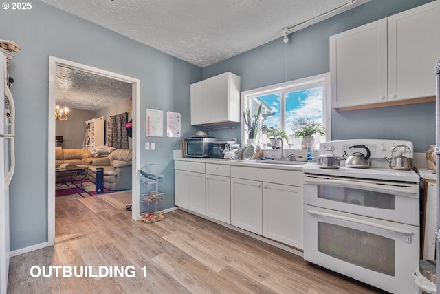 kitchen with white cabinets, light wood-style flooring, a textured ceiling, double oven range, and a sink