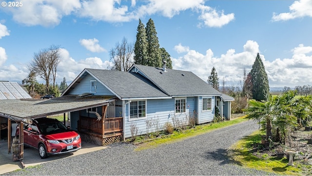 view of side of property featuring driveway, a shingled roof, and an attached carport