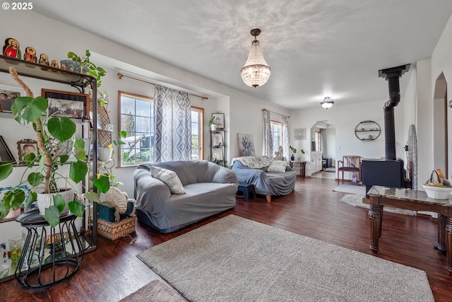 living room featuring wood finished floors, a wood stove, and a healthy amount of sunlight