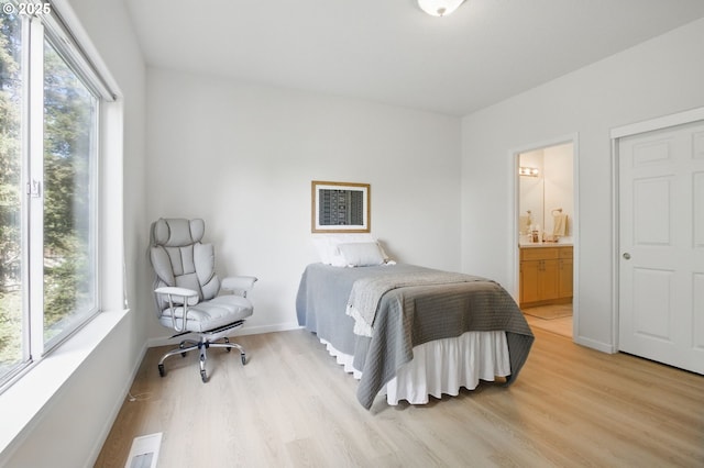 bedroom featuring light wood-style flooring, ensuite bath, and baseboards