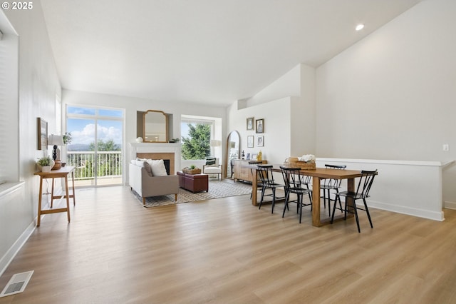 dining space with light wood-style flooring, lofted ceiling, baseboards, recessed lighting, and a fireplace
