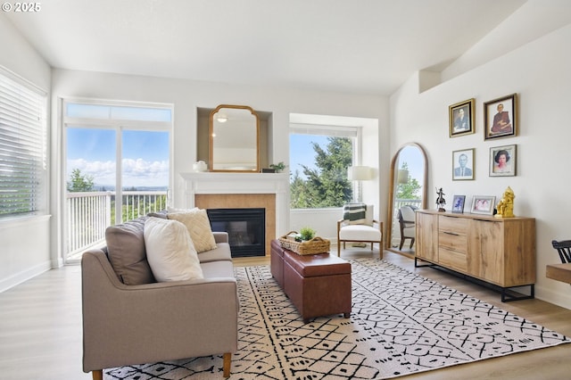 living area with a tile fireplace, light wood-type flooring, and baseboards