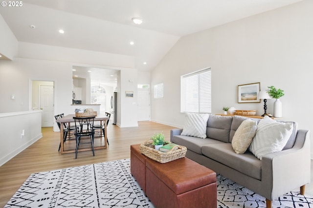 living area featuring light wood-type flooring, lofted ceiling, recessed lighting, and baseboards