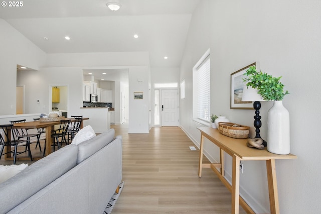 living room with light wood finished floors, recessed lighting, and high vaulted ceiling