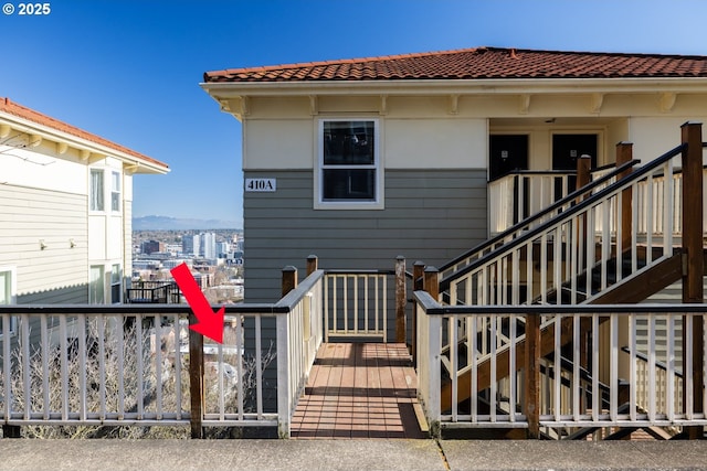 rear view of property featuring a tiled roof and stairway