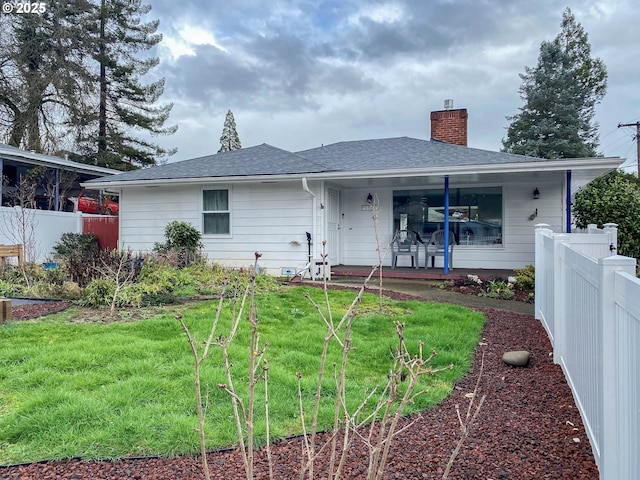 rear view of house with a shingled roof, fence, a lawn, and a chimney