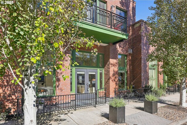 109 SW Gibbs St, Portland, OR 97239 - view of exterior entry featuring french doors, brick siding, and a balcony