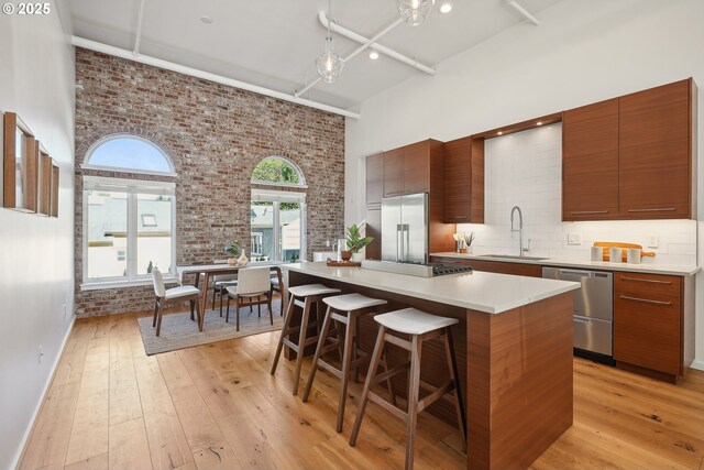 109 SW Gibbs St, Portland, OR 97239 - kitchen featuring appliances with stainless steel finishes, a sink, brick wall, a towering ceiling, and modern cabinets