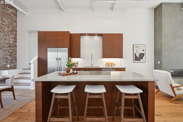 109 SW Gibbs St, Portland, OR 97239 - kitchen with built in fridge, a sink, light wood-type flooring, a towering ceiling, and a kitchen breakfast bar