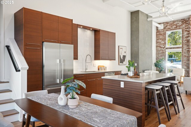 109 SW Gibbs St, Portland, OR 97239 - kitchen with high end fridge, modern cabinets, a sink, light countertops, and a high ceiling