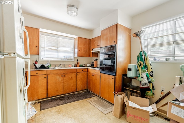 9023 SE Ankeny St, Portland, OR 97216 - kitchen featuring brown cabinets, a sink, freestanding refrigerator, under cabinet range hood, and oven