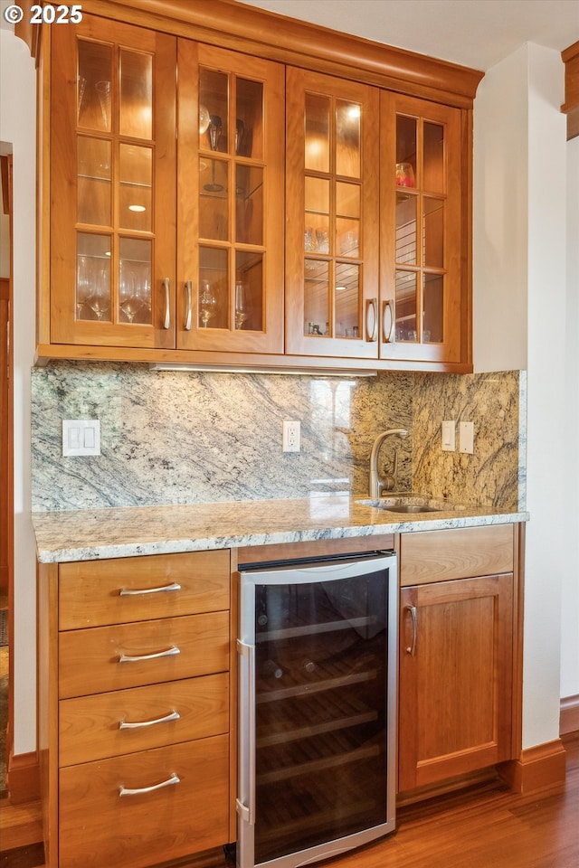 bar with wine cooler, sink, tasteful backsplash, and light stone countertops