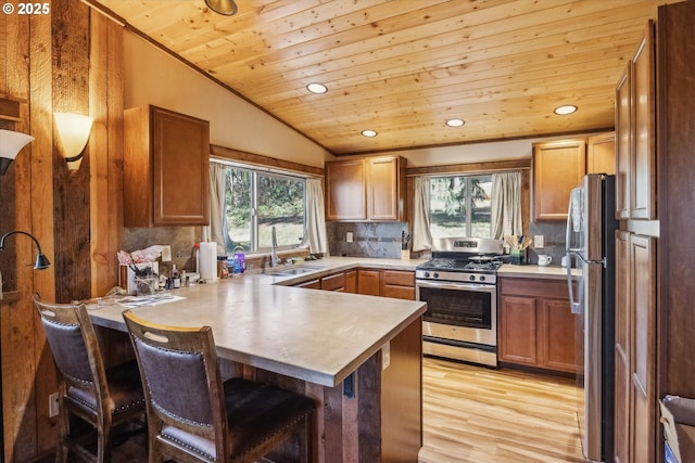 kitchen with a breakfast bar area, vaulted ceiling, wooden ceiling, stainless steel appliances, and backsplash