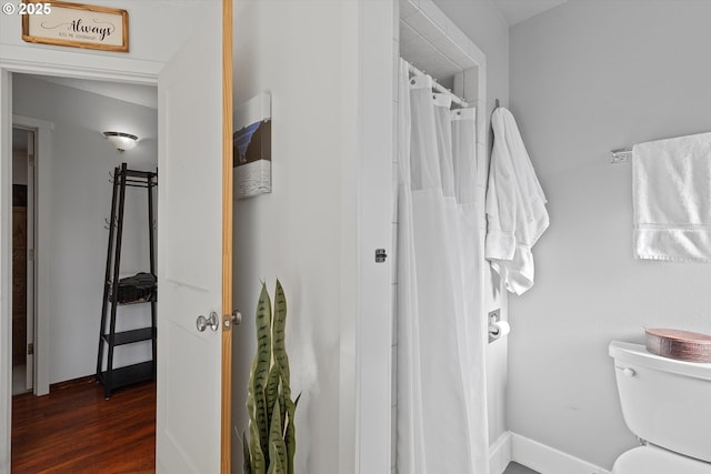 bathroom featuring hardwood / wood-style floors, toilet, and a shower with shower curtain