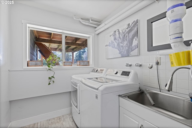 washroom with cabinets, separate washer and dryer, sink, and light wood-type flooring