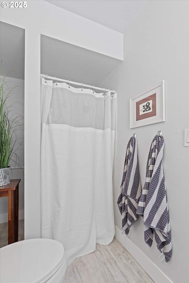 bathroom with hardwood / wood-style flooring, a shower with curtain, and toilet