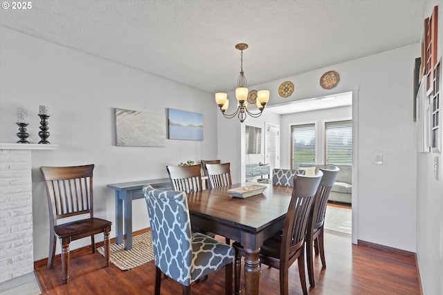 dining room featuring dark hardwood / wood-style flooring, a textured ceiling, and an inviting chandelier