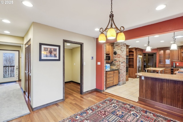 kitchen featuring stainless steel appliances, light hardwood / wood-style floors, a chandelier, and pendant lighting