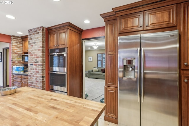 kitchen featuring light colored carpet, wooden counters, and appliances with stainless steel finishes