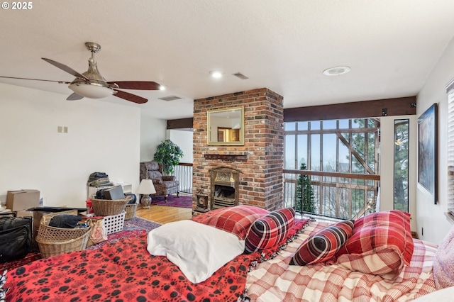 living room featuring a brick fireplace, ceiling fan, and wood-type flooring