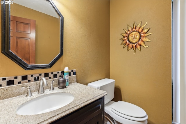 bathroom featuring tasteful backsplash, vanity, and toilet