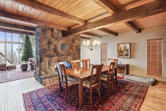 dining space with wooden ceiling, light wood-type flooring, a notable chandelier, and beam ceiling