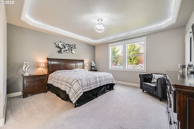 carpeted bedroom with a tray ceiling and a textured ceiling