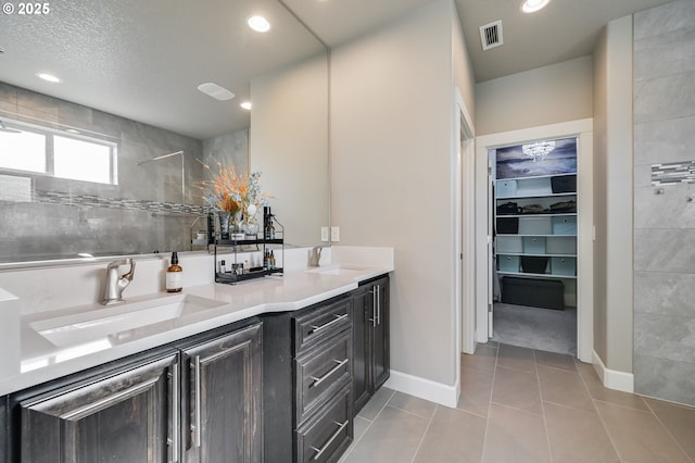 bathroom featuring tile patterned floors, a tile shower, and vanity