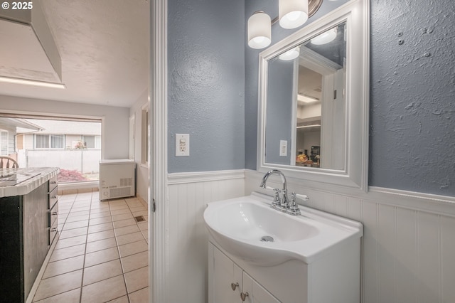 bathroom featuring a wainscoted wall, vanity, a textured wall, and tile patterned floors