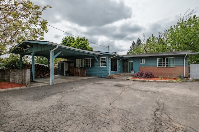 single story home featuring asphalt driveway, fence, an attached carport, and brick siding