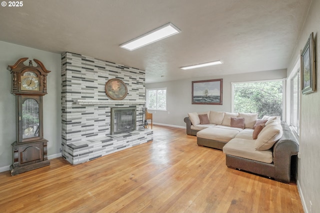 living room featuring wood finished floors, baseboards, and a tiled fireplace