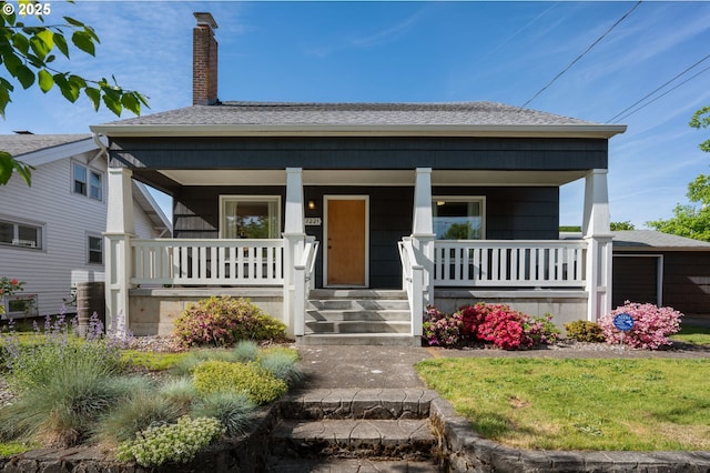bungalow-style home with a chimney, a porch, and a shingled roof
