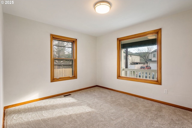 empty room with baseboards, visible vents, and carpet flooring