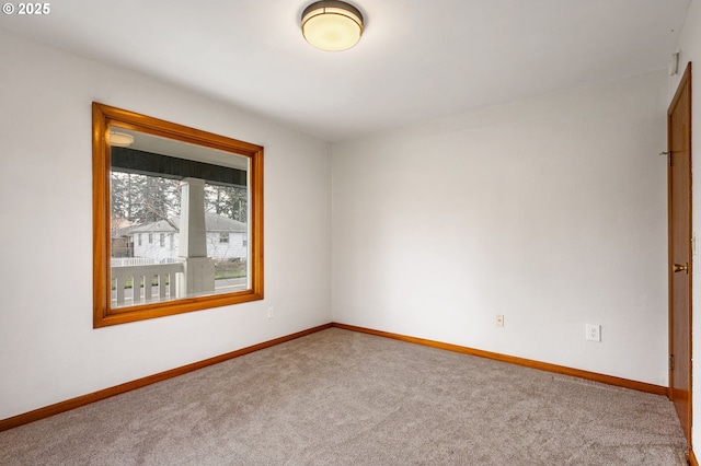 carpeted spare room featuring baseboards