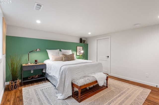 bedroom with wood finished floors, visible vents, recessed lighting, and baseboards