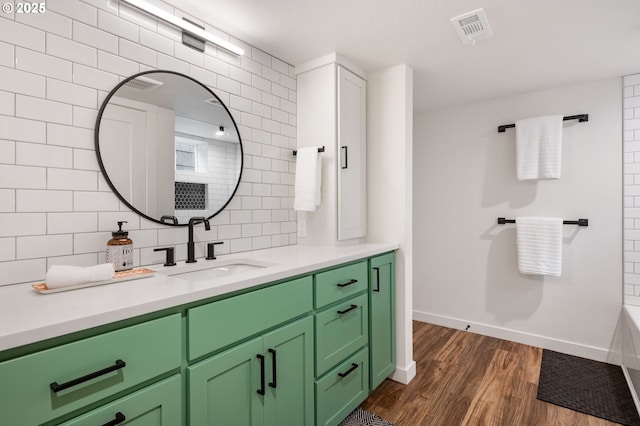 full bathroom with tasteful backsplash, visible vents, baseboards, wood finished floors, and vanity