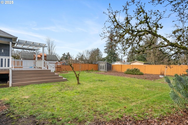 view of yard with an outbuilding, a storage shed, a deck, a pergola, and a fenced backyard