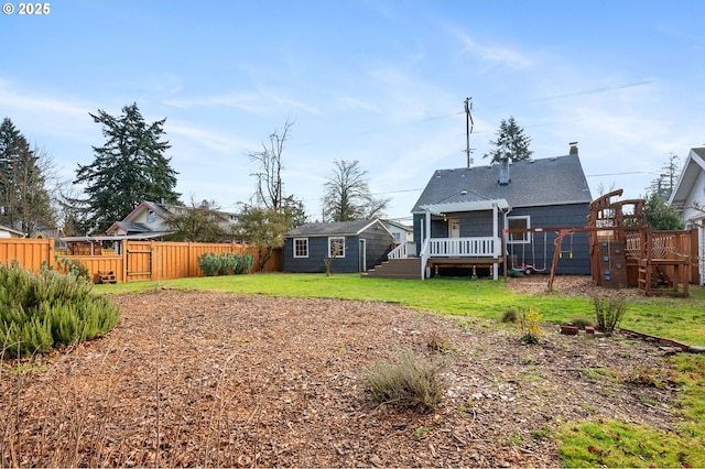 back of house with a deck, a yard, an outdoor structure, and a fenced backyard