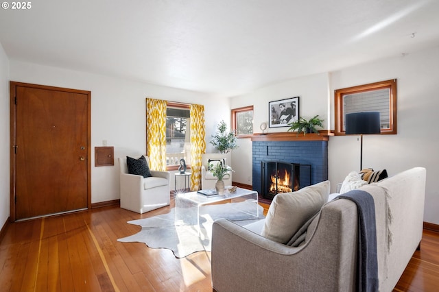 living area featuring wood-type flooring, a fireplace, and baseboards