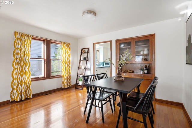 dining area featuring visible vents, light wood-style flooring, and baseboards